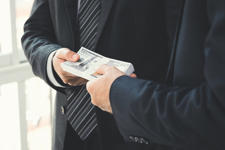 Businessmen secretly passing money to his partner - bribery and corruption conceptsの写真素材