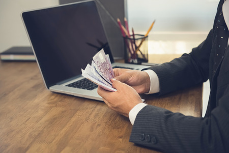 Businessman counting money, Euro banknotes, at his working deskの写真素材