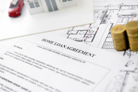 Home loan agreement form paper with house model, blueprint and some money on the table - real estate financial conceptの写真素材