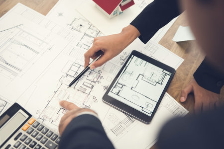 Architects or interior designers discussing floor plan blueprints on the table
