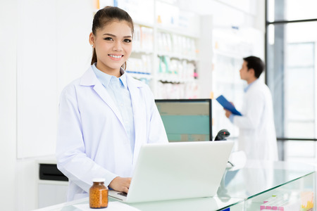 Smiling Asian female pharmacist working in chemist shop or pharmacyの写真素材