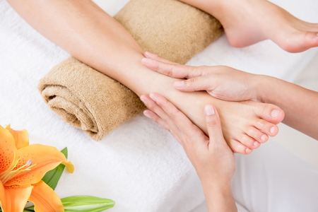Professional therapist giving relaxing reflexology foot massage to a woman in spaの写真素材