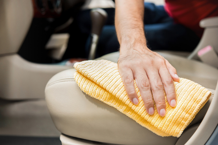A man cleanining beige leather car seat with microfiber cloth - auto detailing and valeting conceptの写真素材