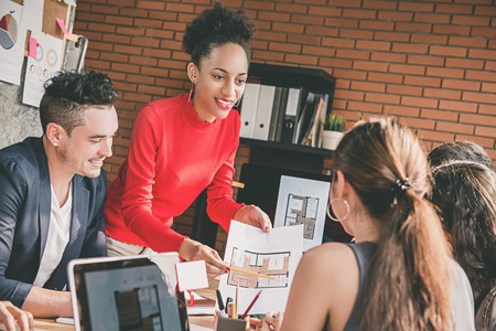 Architect or interior designer businesswoman sharing floor plan layout project ideas with her multiethnic colleagues in the officeの写真素材