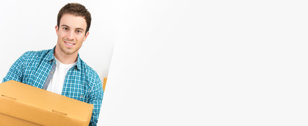 A handsome caucasian man carrying a courier box into new house - horizontal web banner with copy space on the rightの写真素材