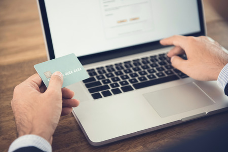 Businessman using laptop computer shopping online and paying with credit card - financial technology (or fintech) conceptの写真素材