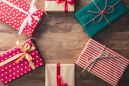 Colorful new year and Christmas holiday gift boxes ideas, top view, on wood table background with hexagon copy space in the middleの写真素材