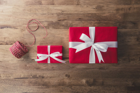 Top view of colorful red Christmas and New Year holiday gift boxes with white ribbon bows and roll...