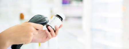 Pharmacist scanning medicine bottle with barcode scanner in pharmacy - panoramic banner with copy space on the rightの写真素材