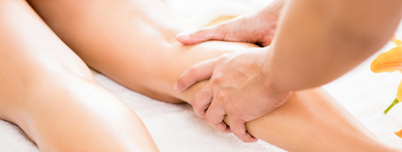 Professional therapist giving relaxing reflexology Thai oil leg massage treatment to a woman in spa - panoramic bannerの写真素材