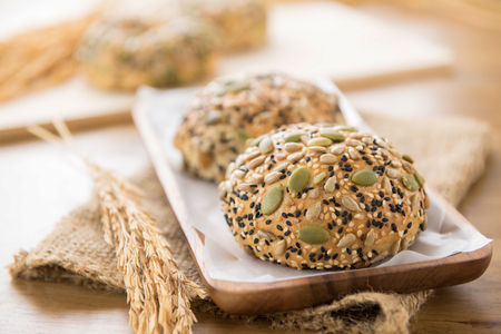 Multigrain mixed cereal seed healthy bread buns in wooden plate displaying with on brown jute sack texture at the tableの写真素材