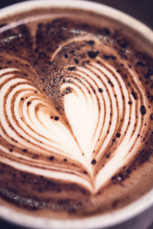 Close up of heart shape latte art on top of hot dark chocolate drink in the cup