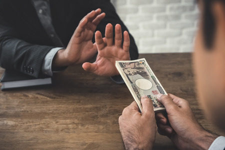 Businessman rejecting money, Japanese yen currrency,  from his partner - anti birbery and corruption conceptの写真素材