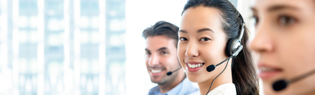 Smiling beautiful Asian woman working in call center office with international team as the customer care operators in  banner backgroundの写真素材