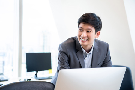 Young smiling Asian chinese businessman working in the officeの写真素材
