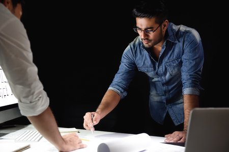 Asian architect team staying late at night in office discussing  project at meeting tableの写真素材