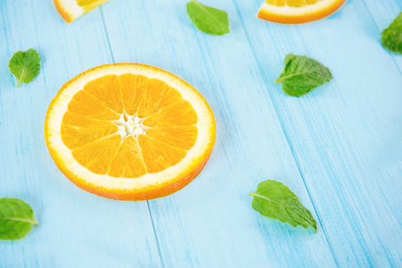 Fresh fruit for summer, juicy sliced oranges with pepperment leaves on pastel light blue wood backgroundの写真素材