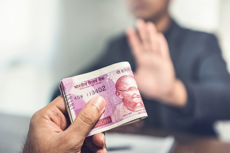 Businessman offering money in the form of Indian Rupee currency as a bribeの写真素材