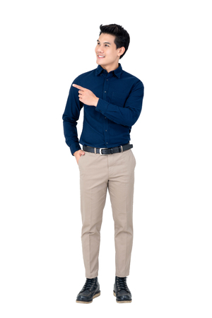 Studio portrait of sophisticated handsome smiling young Asian man wearing semi formal clothing while pointing at space asideの写真素材