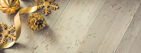 Golden curly ribbon and shimmer Christmas decorating items on wood banner background at border with copy space on the rightの写真素材