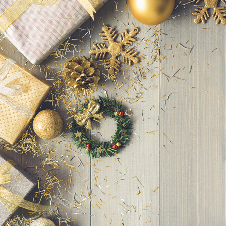 Silver and gold gift boxes and glittering Christmas decorating items on wood background top view with copy spaceの写真素材