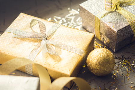 Sliver and gold shimmer Christmas gift boxes with glittering decoration items on wood table for festive seasonの写真素材