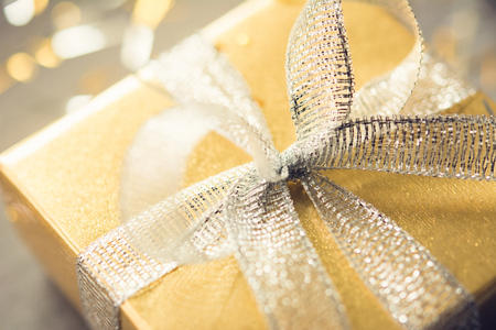 Close up of Christmas gift box with shiny glittering silver ribbon bow and gold wrapping paperの写真素材