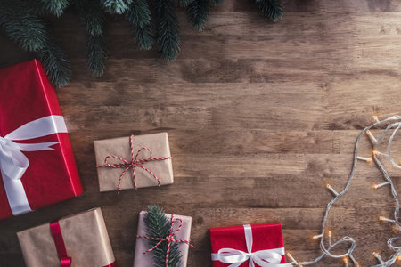 Christmas and new year background with gift boxes, string light and green pine decorations on wood...
