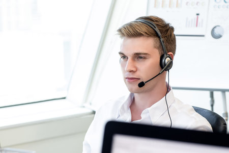 Handsome English businessman wearing microphone headset working in the office as customer care staff