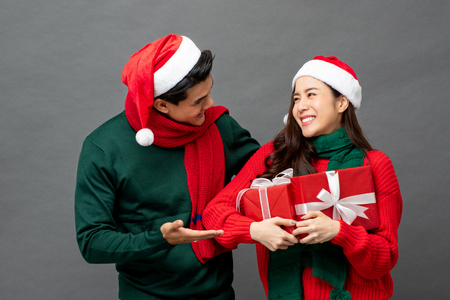 Happy Asian woman being surprised with Christmas gift boxes by her boyfriendの写真素材