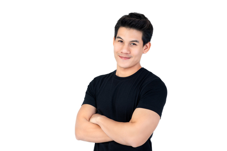 Smiling handsome Asian man in casual black t-shirt with arm crossed looking at camera studio shot isolated on white backgroundの写真素材
