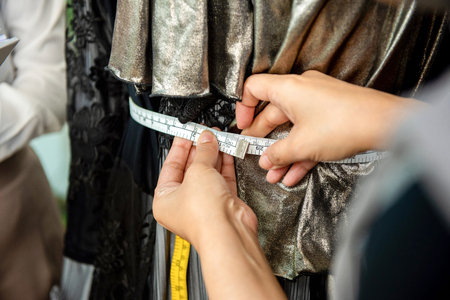 Close up shot of a female designer hand using a measuring tape on a customers waistlineの写真素材
