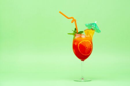 Colorful alcoholic cocktail drink in the glass decorated with wedged pineapple, mint and umbrellaの写真素材