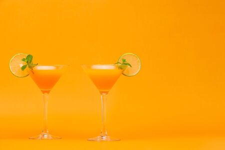 Refreshing orange juice cocktail drinks in the glasses on colorful backgroundの写真素材