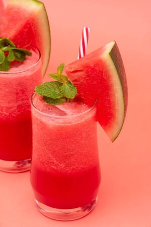 Refreshing cold watermelon fruit juice smoothies drinks in the glasses on coral pink backgroundの写真素材
