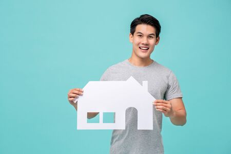 Portrait of young handsome Asian man holding paper home for real estate conceptの写真素材