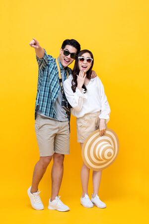 Happy excited young Asian couple tourists in colorful yellow backgroundの写真素材