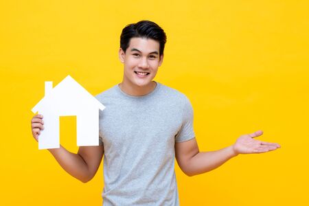 Portrait of young handsome Asian man holding paper home for real estate conceptの写真素材
