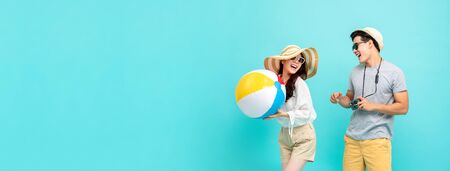 Playful Asian couple in summer casual clothes with beach accessories studio shot isolated on light blue banner background with copy spaceの写真素材