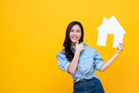 Portrait of young happy excited Asian woman holding paper home for real estate conceptの写真素材