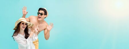 Playful Asian couple in summer beach casual clothes on light blue banner background with copy spaceの写真素材