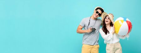 Playful Asian couple in summer casual clothes with beach accessories studio shot isolated on light blue banner background with copy spaceの写真素材