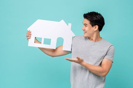 Portrait of young handsome Asian man holding paper home for real estate conceptの写真素材