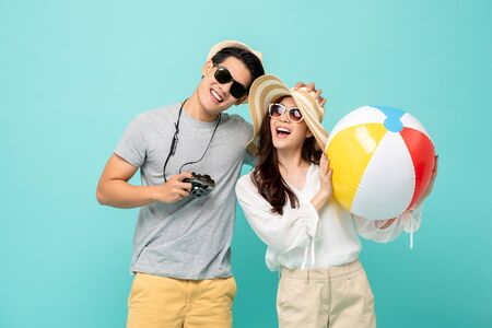 Lovely Asian couple in summer casual clothes and beach accessories studio shot isolated on light blue backgroundの写真素材