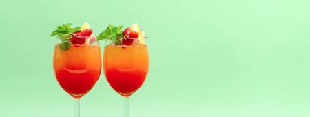 Refreshing colorful sunrise fruit cocktail drinks on  pastel green banner background with copy spaceの写真素材