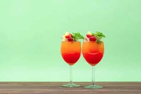 Refreshing colorful sunrise fruit cocktail drinks on wood table in pastel green backgroundの写真素材