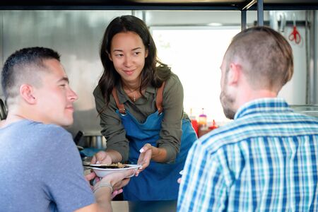 Young Asian woman food truck business owner serving food to a customerの写真素材