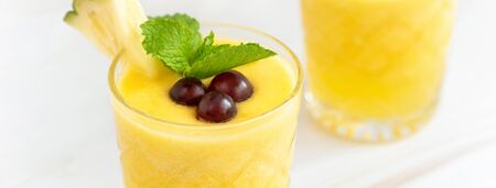 Close up shot of chilled refreshing pineapple summer drink on marble table background, banner sizeの写真素材