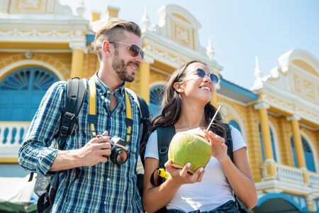 Portrait of happy interracial tourist couple taking a break having a coconut drink while enjoying their tour in Bangkok thailandの写真素材
