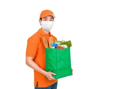 Hygienic man wearing medical mask carrying supermarket grocery shopping bag offering home delivery service isolated in white backgroundの写真素材
